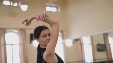 Dans stüdyosundaki profesyonel balerin kadın portresi. Bale sınıfı eğitimi. Bale okulu konsepti. Büyük pencereli bir dans salonunda dönen bir balerin. Ağır çekim. Yüksek kalite FullHD