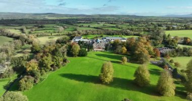 Yeşil çimlerin üzerinde bir malikane. Köy evi ya da köy evi. Yeşil çimlerin üzerinde şık bir ev. Doğanın arka planına karşı köy ikametgahı. İrlanda Kır Evi ve Kilkenny Bahçeleri yüzüğü