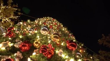 Işıldayan süsler ve parlak ışıklarla süslenmiş canlı bir Noel ağacı, tatil ruhunu sergiliyor. Sıcak Noel atmosferi. Yüksek kalite 4k görüntü