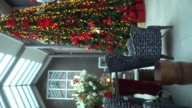 Dikey. Evde Noel ağacı var. Noel arifesi ve yeni yıl için hazırlık. Modern bir iç mekanda karşı konulmaz bir Noel ağacı. Yeni yıl, modern bir evin içinde Noel ağacı.