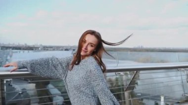 Şık ve şık saçlı bir kadın büyüleyici gülümsemesini sergilerken canlı şehir manzarasından zevk alıyor. Kyiv, Ukrayna, 2021. Ağır çekim. Yüksek kaliteli HD görüntüler