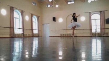 Sivri pabuçlu baş balerin ve beyaz bale eteği, piruet yapar. Dans stüdyosundaki genç klasik dansçı kadın. Bale sınıfı eğitimi. Bale okulu konsepti. Dans salonunda dönen bir balerin