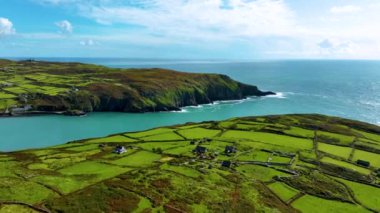 Bu hava görüntülerinde, kayalıklara tepeden bakan deniz ve karayı harmanlayan bir uçurumun tepesinde küçük bir köy bulunan çarpıcı kıyı manzaraları sergilenmektedir. Cape Clear Adası. Glen East, Co. Cork, İrlanda. Yüksek