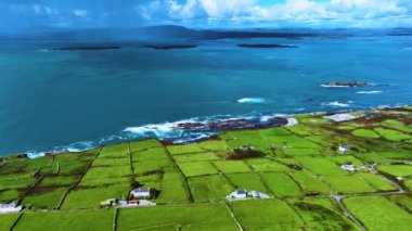 Vahşi doğanın sinematik hava manzarası dünyaca ünlü kıyı şeridi. Sahildeki kayalık doğa arka planı. Vahşi Atlantik Yolu. Güzel doğa, insansız hava aracı okyanusun ve yeşil kayalık adaların üzerinde uçar.