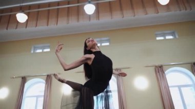 Sivri ayakkabılı baş balerin ve siyah bale elbisesi çok güzel dans figürleri gösteriyor. Büyük salonda klasik balerin unsurlarıyla dans eden zarif balerin. Dans stüdyosu sahne ışığında bale yapıyor.