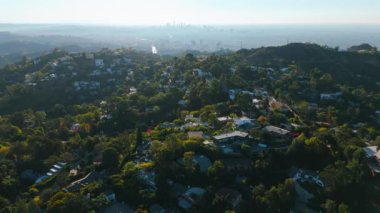 Bu büyüleyici video bereketli yeşilliklerle çevrili sakin bir yerleşim bölgesinin havadan görüntüsünü sunuyor, evleri canlı bir ufuk çizgisiyle harmanlıyor. Universal City, Los Angeles, California, ABD. Yüksek kalite