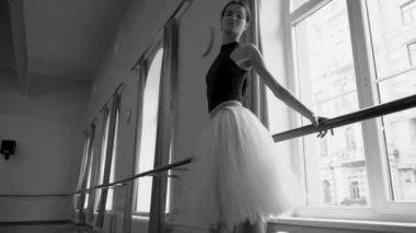 Beyaz etekli genç balerin dans sınıfında bale pozisyonu alıyor. Dans stüdyosundaki genç klasik dansçı kadın. Bale sınıfı eğitimi. Bale okulu konsepti. Yavaş