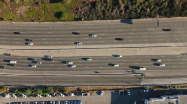 Hava görüntüsü, manzaraya derinlik katan bir köprü ile tamamlanmış, çok sayıda arabanın dinamik bir trafik akışı yarattığı işlek bir otoyol ortaya koyuyor. Universal City, Los Angeles, California, ABD, 2024. Yüksek