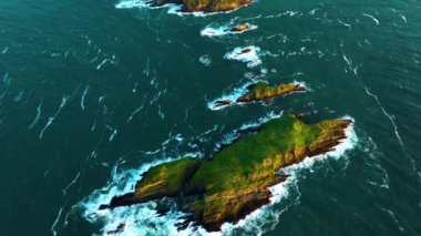 Nefes kesen hava çekimlerinde kayalık adalar canlı turkuaz sulara ve çarpışan köpük dalgalarına karşı kurulur. County Cork 'ta. İrlanda, yüksek kalite 4K görüntü 