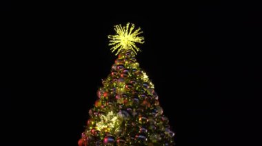 Güzel aydınlatılmış bir Noel ağacı yıldızlarla dolu huzurlu gece gökyüzüne karşı ışıldıyor. Oyuncaklarla süslenmiş yeşil ağaç, hediyeler, hediye kutuları, yanıp sönen çelenkler, yanan lambalar