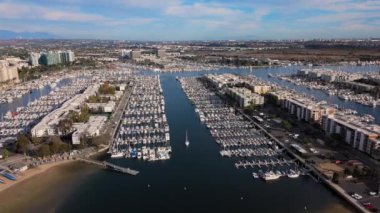 Bu çarpıcı hava fotoğrafı canlı bir şehir siluetine karşı kurulmuş çeşitli teknelerle dolu hareketli bir marinayı yakalıyor. Marina del Rey, Los Angeles, ABD. 2024. Yüksek kalite 4k görüntü