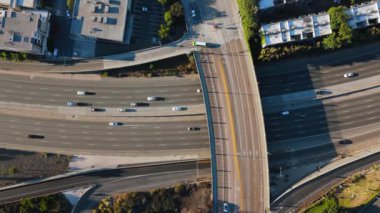 Bir hava manzarası, manzaraya derinlik katan bir köprü tarafından tamamlanan ve çok sayıda arabanın dinamik bir trafik akışı yarattığı yoğun bir otoyolu ortaya koyuyor. Universal City, Los Angeles, California, ABD, 2024. Yüksek