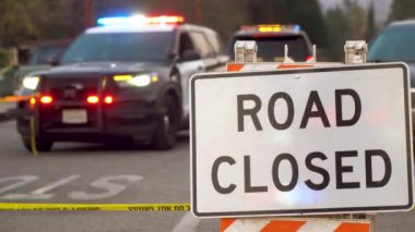 Pasadena, Kaliforniya 'da 10 Ocak 2025' te yakalanan ve ışıkları yanıp sönen kolluk kuvvetleri araçları tarafından uygulanan yol kapanışının ayrıntılı bir sahnesi. Ön planda 