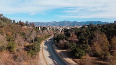 Pasadena, Kaliforniya 'daki tarihi Colorado Street Köprüsü' nün çarpıcı hava görüntüsü, açık bir günde arka planda San Gabriel Dağları ile birlikte çekildi. Sahne köprüleri vurguluyor