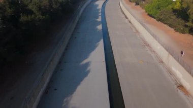 Los Angeles Nehir Kanalı 'nın sinematik insansız hava aracı üzerinde beton nehir yatağı, kıvrımlı su akıntısı ve çevreleyen şehir yeşilliği sergileniyor. Bu görüntüler doğanın yan yana gelişini vurgular.