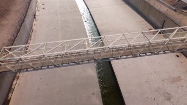 Bir hava görüntüsü, beton bankalar ve çorak arazilerle çevrili bir kanalı zarifçe geçen bir köprüyü yakalar. Colfax Caddesi, Los Angeles, Kaliforniya, ABD, Kasım 2024. Yüksek kalite 4k görüntü 