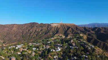 Havadan bakıldığında, berrak mavi gökyüzünün altındaki gür California tepelerine kurulmuş ikonik Hollywood tabelası görülüyor. Sinematik Los Angeles tarihi Hollywood sinemacılığı. Los Angeles