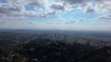 Los Angeles 'ın uçsuz bucaksız siluetini gösteren nefes kesici hava görüntüleri Hollywood Tepeleri' nden şehir manzarasına yayılıyor. Şehir manzarası yuvarlanan tepeler, lüks konutlar tarafından çerçevelenmiştir.