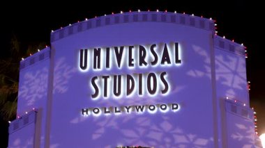 Hollywood Universal Stüdyoları 'nın ikonik girişini gösteren editör görüntüleri, festival ışıkları ve sanatsal kar tanesi projeksiyonlarıyla aydınlatılıyor. Tanınabilir işaret ve zarif ışıklandırma