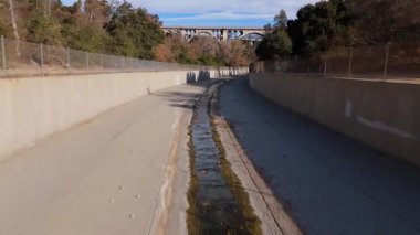 Colorado Caddesi Köprüsü 'nün altındaki kuru bir kanalın sakin bir görüntüsü. Yangından birkaç gün önce çekildi. Beton kanal yemyeşil, ağaçlarla kaplı bir arazide akıyor.