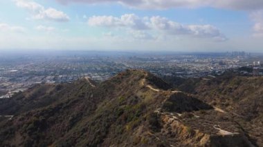 Los Angeles 'taki Runyon Canyon Parkı' nın çarpıcı hava görüntüleri. İnsansız hava aracı engebeli tepelerin arasından süzülen manzaralı bir yürüyüş yolu yakalar ve genişleyen panoramik manzaraya doğru yol alır.