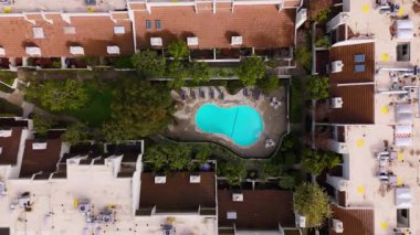 Kamera nazikçe turkuaz suya doğru inerken, Los Angeles, Studio City 'deki sakin bir havuzun insansız hava aracı görüntüleri. Havuz alanı yemyeşil ve modern renklerle çevrili.