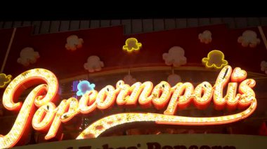 25 Aralık 2024 'te Los Angeles, Kaliforniya' da gece aydınlatılmış Popcornopolis neon ışıklarının canlı bir yakın çekimi çekildi. Parlak altın ışıklar ve şakacı patlamış mısır şekilli dekorasyonlar