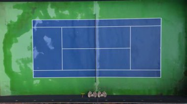 Los Angeles, Studio City 'de yemyeşil yemyeşil bir alanda canlı bir mavi tenis kortu yakalayan hava aracı görüntüleri. Kamera yükselir ve mahkemenin ıslak yüzeyini gösterir.