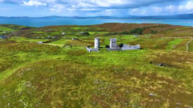 Havadan. Büyük bir adanın tepesinde antik bir deniz feneri. Atlantik Okyanusu 'nun ortasındaki yeşil bir adada antik bir deniz feneri. Yeşilin ortasındaki antik bir kalenin kalıntıları.