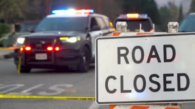 Pasadena, Kaliforniya 'da 10 Ocak 2025' te yakalanan ve ışıkları yanıp sönen kolluk kuvvetleri araçları tarafından uygulanan yol kapanışının ayrıntılı bir sahnesi. Ön planda 