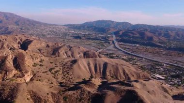 Los Angeles, Kaliforniya 'daki Ebey Kanyonu' nun engin ve engebeli arazisini gösteren çarpıcı hava görüntüleri. Kuru tepeleri, dolambaçlı yolları ve içinden geçen büyük bir otoyolu yakalıyor.
