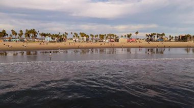 10 Ekim 2024 'te, Santa Monica Sahili, Kaliforniya, ABD' yi yavaş çekimde çekiyoruz. Videoda yumuşak okyanus dalgaları, altın kum, palmiye ağaçları ve kıyı manzarasından hoşlanan insanlar sergileniyor.