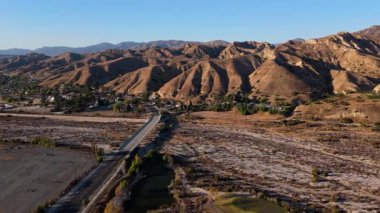 Kuru araziyi kesen kırsal bir yol ile manzaralı bir dağ manzarası üzerinde ilerleyen bir İHA uçağını yakalamak nefes kesici bir görüntü. Altın güneş ışığı, gökyüzünün dokusunu güçlendirir.