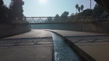 Huzurlu bir kentsel su yolu, yumuşak sabah ışığıyla aydınlatılan güzel tasarlanmış bir köprünün altından zarifçe akar. Colfax Caddesi, Los Angeles, Kaliforniya, ABD, Kasım 2024. Yüksek kalite 4k görüntü 