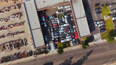 Kalabalık bir otoparkı gösteren, çeşitli araba ve kamyonlarla dolu bir hava manzarası. Araba servisi, araba tamiri. Otoparkta bozuk arabalarla araba servisi. Los Angeles