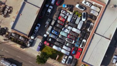 Kalabalık bir otoparkı gösteren, çeşitli araba ve kamyonlarla dolu bir hava manzarası. Araba servisi, araba tamiri. Otoparkta bozuk arabalarla araba servisi. Los Angeles