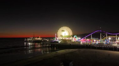 Santa Monica, LOS ANGELES, CALIFORNIA, ABD, 11 Ekim 2024. Gece ışıl ışıl parlayan canlı bir karnavalın çarpıcı hava manzarası, binişler ve pek çok eğlence içeriyor. Direksiyondaki gülen surat