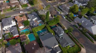 Los Angeles 'taki Studio City' nin banliyölerinde tek kişilik evler, ağaçlarla kaplı caddeler ve özel yüzme havuzlarının sergilendiği havadan çekilmiş bir fotoğraf. Dinamik hareket yakalar