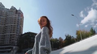 Neşeli bir kadın süveter giyiyor ve sokaklarda olumlu duygular sallayarak yürüyor. Kafkasyalı mutlu bir kız açık havada dans eder, tek başına eğlenir ve içtenlikle güler. Saç gelişir