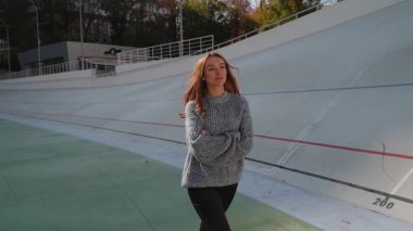 Güzel bir kadın canlı bir bisiklet pistinde kendine güvenerek duruyor. Modern spor havasını tarzı ve enerjisiyle sergiliyor. Modern şehir yaşam tarzı ve mutluluk kavramı. Ağır çekim. Yüksek kalite