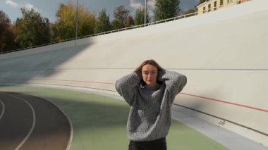Genç bir kadın, canlı sonbahar yeşillikleriyle çevrili güzel ve manzaralı bir spor pistinde hareketli bir koşudan hoşlanıyor. Modern şehir yaşam tarzı ve mutluluk kavramı. Ağır çekim. Yüksek kaliteli HD