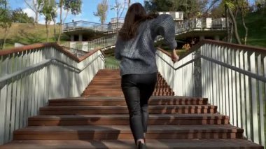 Bu video, bir kadının zarif bir şekilde parkta yürürken, ahşap merdivenlerden çıkarken, zindelik ve neşeyi somutlaştırdığını gösteriyor. Modern şehir yaşam tarzı ve...