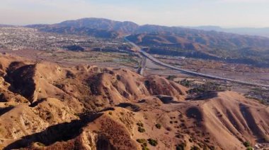 Los Angeles, Kaliforniya 'daki Ebey Kanyonu' nun engin manzarasını gösteren hava görüntüleri. Görüntülerde, kayan tepeler, engebeli arazi ve vadiyi kesen bir otoban görülüyor.