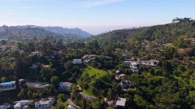 İnsansız hava aracı görüntüleri Los Angeles, Kaliforniya 'daki yemyeşil bir tepede yavaşça yükseliyor. Kamera yeşil vadileri, lüks evleri ve sık ağaçların arasına yerleştirilmiş dolambaçlı yolları yakalıyor. Doğaldır