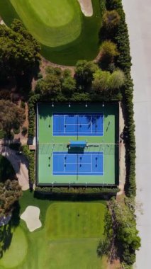 17 Mart 2025 'te çekilen dikey hava görüntüleri, yeşil ve yakındaki golf sahalarıyla çevrili iki açık mavi tenis kortunun yavaş yavaş alçaldığını gösteriyor. Huzurlu sahne