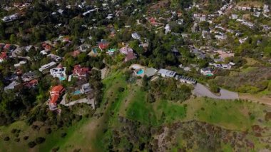 Los Angeles 'ın yemyeşil yeşilliklerine yerleşmiş lüks dağ evlerinin hava görüntüleri. İnsansız hava aracı ileri uçuyor, havuzlu modern villaları, manzaralı virajlı yolları ve panoramik manzaralı