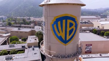 Warner Bros. Stüdyoları 'nın 4000 Warner Blvd, Burbank, California' daki su kulesinin yörüngesindeki insansız hava aracı. İkonik yapı stüdyo binaları, aşamaları ve üretimle çevrilidir.