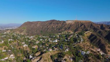 10 Ekim 2024 'te Los Angeles, ABD' deki Hollywood tabelasını ve lüks tepe kenarındaki evleri görüntülemek için Hollywood Tepeleri üzerinde ilerleyen havadan çekimler yapıldı. Manzaralı manzara engebeli araziyi gösteriyor.