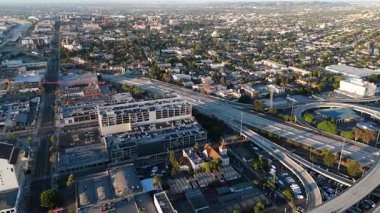 Hava görüntüsü gündoğumunda modern bir otoyol kavşağını ve kentsel gelişimi yakalar. Karmaşık karayolu ağları ve yapılandırılmış şehir planlaması büyüyen bir metropolün dinamik altyapısını vurguluyor