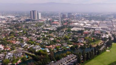 Görünür lüks evler, havuzlar ve ön planda küçük bir göl bulunan Toluca Gölü yerleşim alanı üzerinde uçan insansız hava aracı görüntüleri. Warner Bros. Stüdyoları ve ikonik ses sahneleri